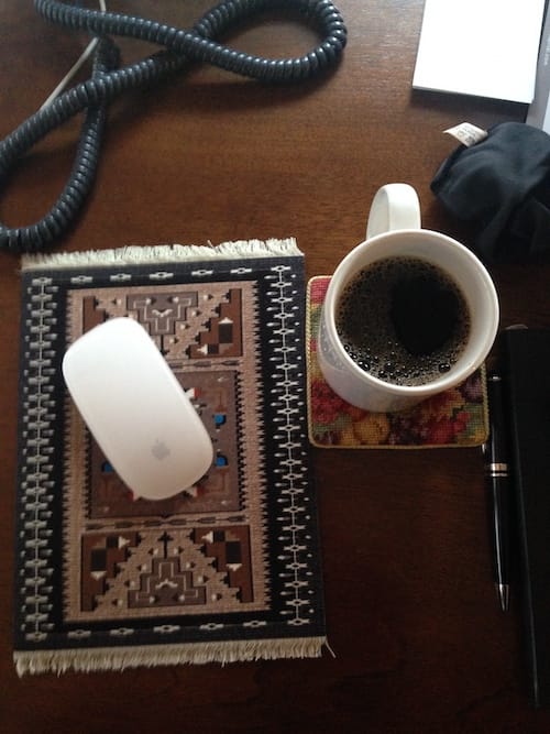 A desk with a computer mouse coffee cup and pen. Coffee test number 3000 or something